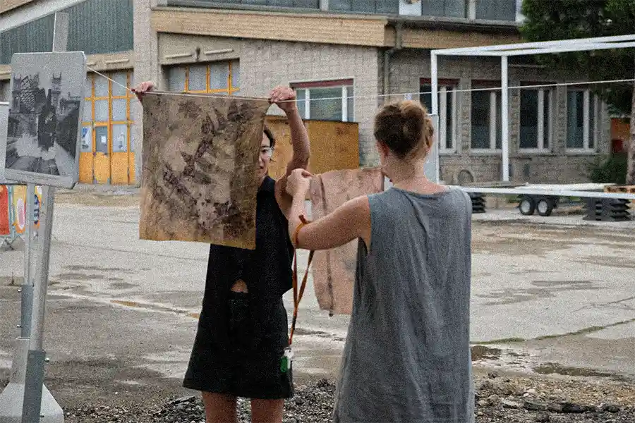 Lili Carr and Madita Kümmeringer hanging plant-dyed fabric patches.